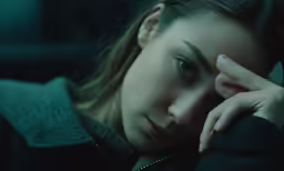 a woman with blue eyes looks off to the side