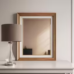 a mirror sitting on top of a white table next to a lamp