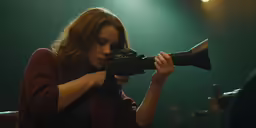 woman holding a large camera on top of a table