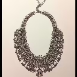 an ornate necklace is displayed in a silver frame
