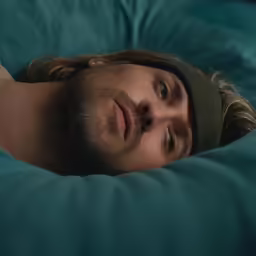 a man laying in bed covered in blue covers