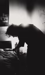 a person bent down in a bed and looking in a window