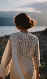 a woman is standing on a beach looking out at the water