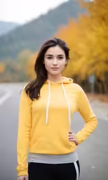 a beautiful woman in yellow shirt standing near trees