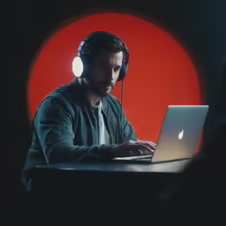 a man wearing headphones working on a laptop computer