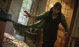 the man stands in front of the bed in a messy room