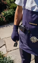 a man wearing a purple apron and a cell phone
