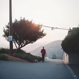 the person is walking down the sidewalk with the street lights