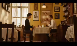 a man sitting in a chair at a table with a woman on her phone