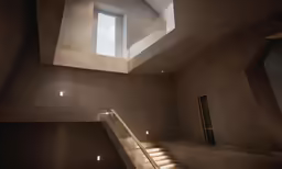 an artistic and contemporary staircase leads to a skylight that appears to be suspended