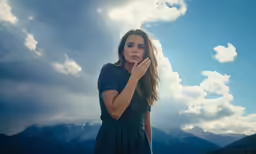 a young lady holding her hand up to her face as the sun shines down