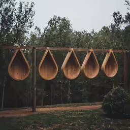 seven wood - lined sculptures sit next to each other in front of trees