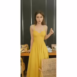 a woman wearing a yellow dress standing in front of a table
