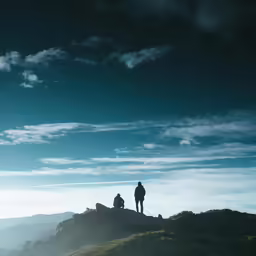 a man is standing on the top of a mountain with his back to the camera, looking over at a beautiful landscape