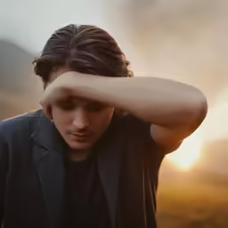 a young man holds his head with his hands