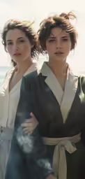 two women walk down the beach while dressed in black and white