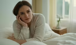 a woman lays on her bed holding a flower