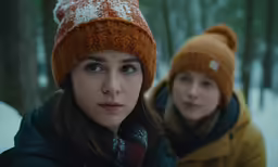 two girls in winter clothes and a sled
