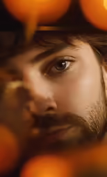 a man looking through a bunch of oranges