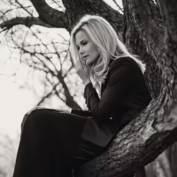 a woman that is sitting on top of a tree