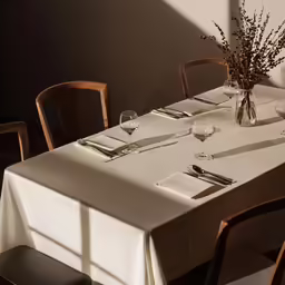 empty restaurant table with white tablecloth and a vase full of flowers