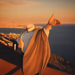 a statue of a person on a ledge pointing towards the water