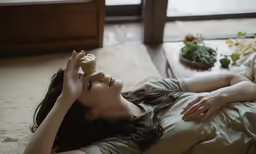 a woman laying on her stomach eating a sandwich on top of a bed
