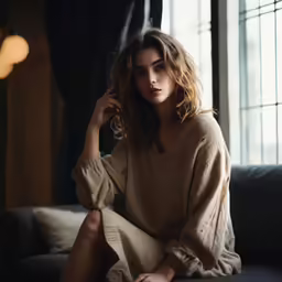 a woman is sitting on a couch wearing a brown outfit