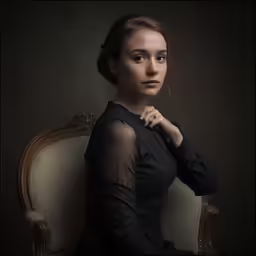 a young woman posing on an antique chair in the dark