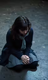 a young woman kneeling and holding her hand to her face