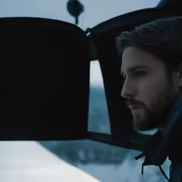 man looking out window of car in the cold