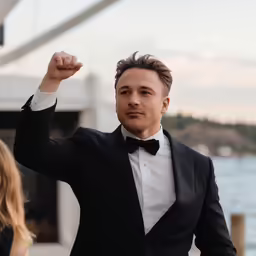 a man in a tuxedo poses while holding his fist