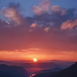 the sun sets over a mountain range with some mountains