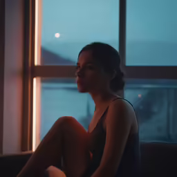a beautiful woman sitting on a sofa in front of a window