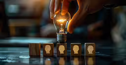 a person with their hand on an electric light bulb,a person pushing wood blocks on top of a table