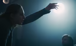 two people in front of a light and one person holding out his hand