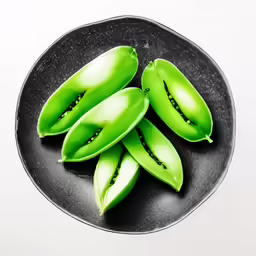 a plate filled with green fruits sitting on top of a table