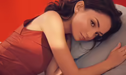 a woman laying on a pillow while posing for a picture