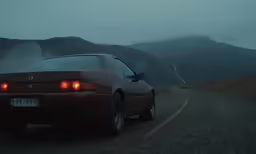 an automobile with its lights on driving down the road