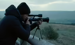a photographer takes pictures of a mountain range on his tripod