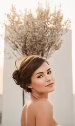 young woman smiling at camera in front of tall tree