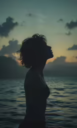 silhouette photograph of girl in water at sunset