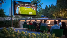 people sitting in chairs in front of a large screen watching a soccer game