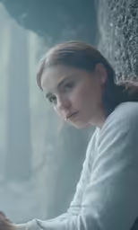 a woman sitting in the forest looking into the distance