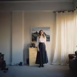 a woman in a white top is standing by the window