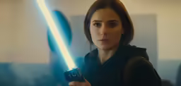 a woman holding a remote and a light saber in her hand