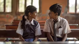 a couple sitting next to each other on top of a wooden bench,two children sitting next to each other on a bench