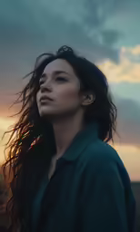 a young woman is looking off into the distance with a stormy sky in the background