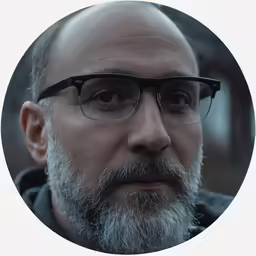 an old man with glasses wearing a grey shirt
