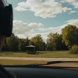 the view out of the window of a car looking at a little pavilion
